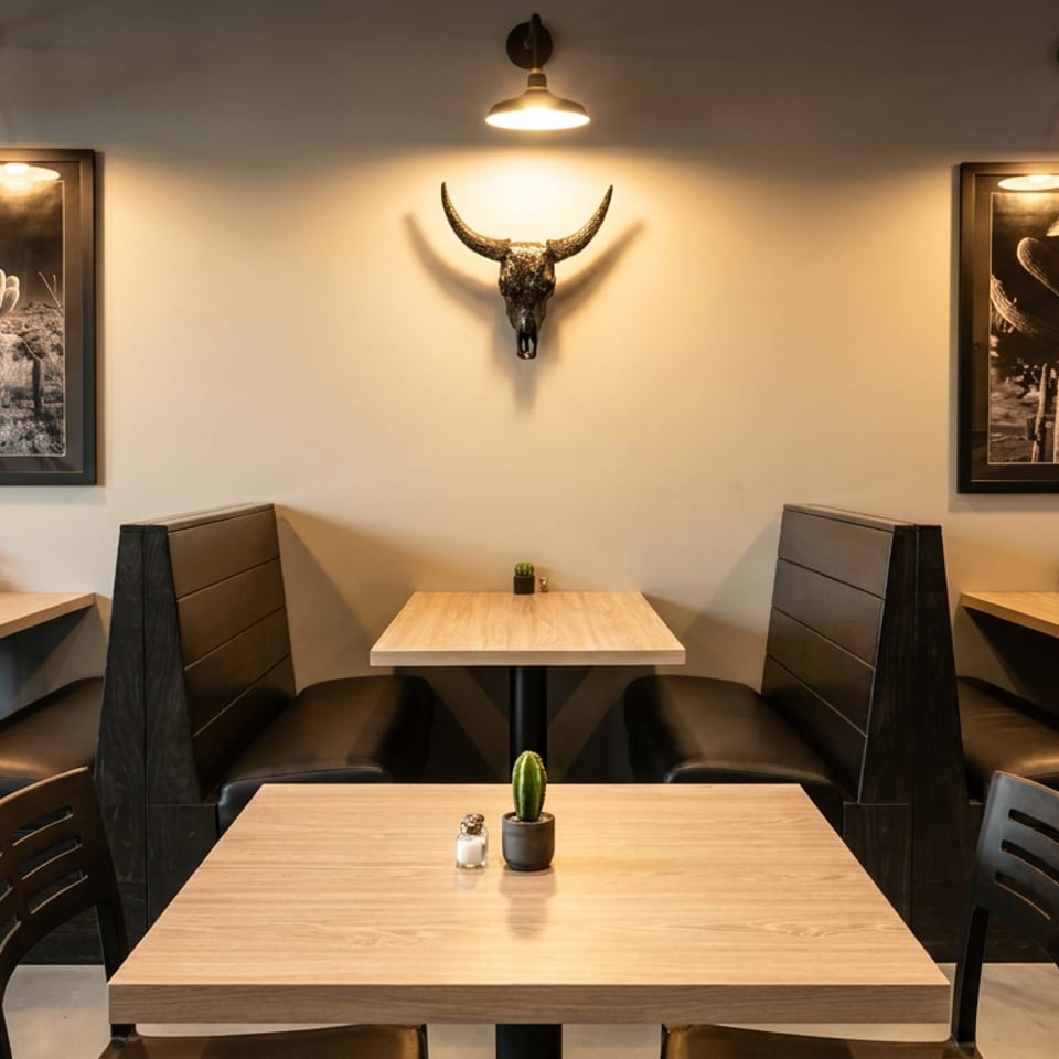Restaurant interior with light wood tables, dark booths, desert art, and a bull skull on the wall.